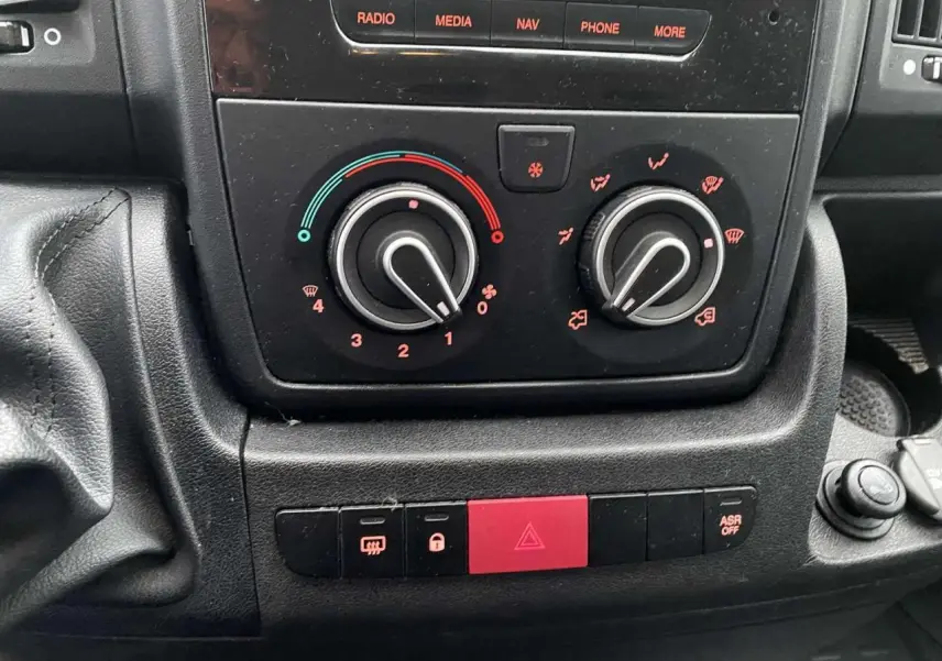 Vue rapprochée du tableau de bord de l'Opel Movano Fourgon 2022, montrant les commandes de climatisation et les boutons d'alerte.