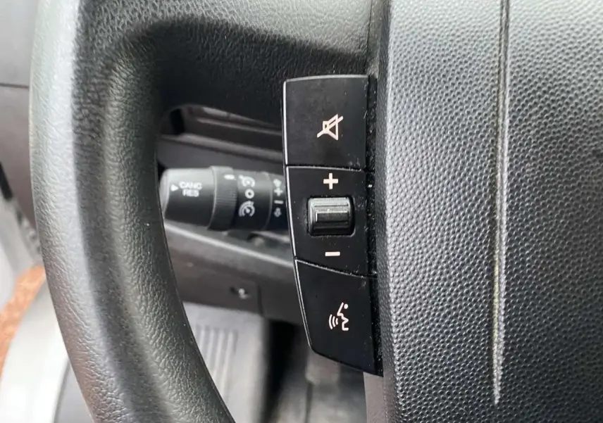 Gros plan sur les commandes au volant du fourgon blanc Opel Movano, avec boutons de volume et commande vocale visibles.