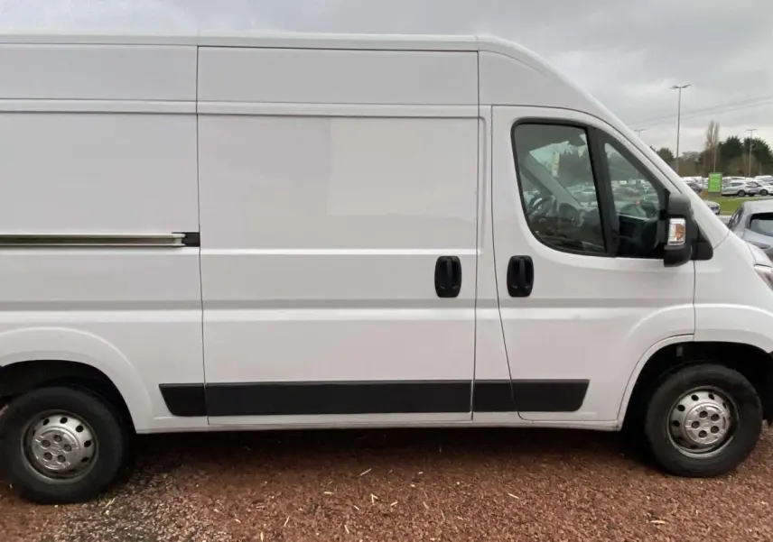 Vue latérale droite d’un utilitaire blanc Opel Movano Fourgon 3.5T L2H2 avec portes coulissantes et protections noires.