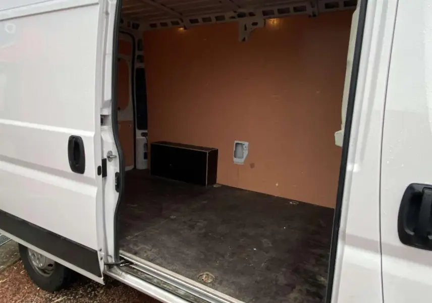 Vue latérale gauche du fourgon blanc Opel Movano 2022 avec porte coulissante ouverte montrant l’intérieur vide et plancher bois.