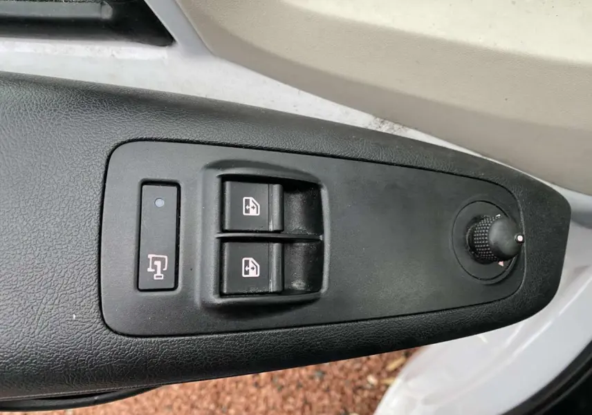 Gros plan sur les commandes de lève-vitres et réglage des rétroviseurs côté conducteur d’un Opel Movano blanc.