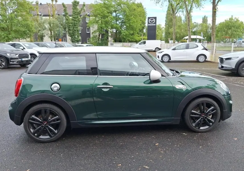 Vue de profil côté gauche d'une MINI S John Cooper Works 2015 vert foncé avec toit blanc et jantes noires.