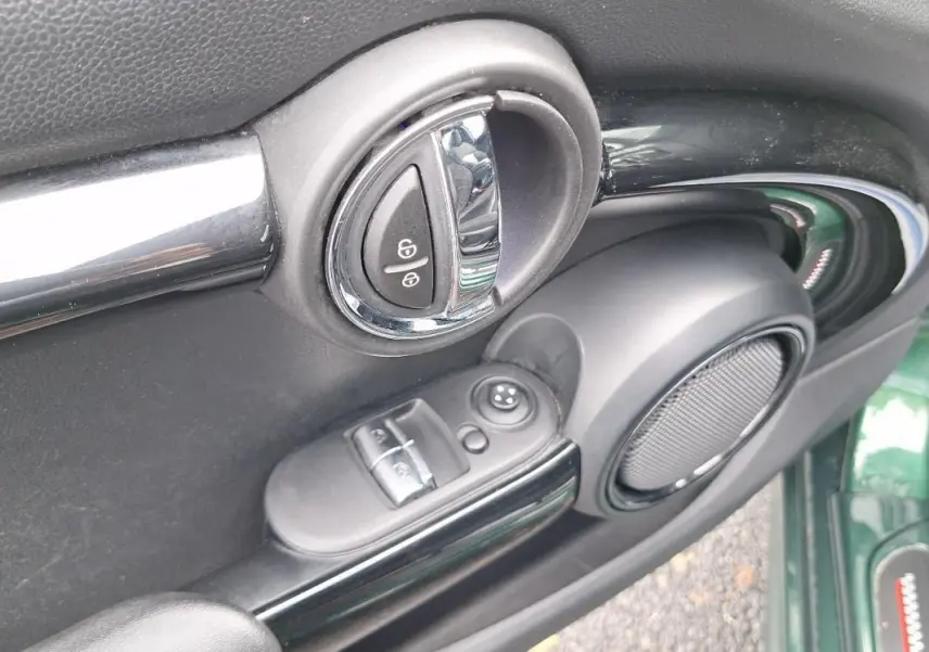 Détail de la porte côté conducteur d'une MINI S John Work 2015 verte, montrant la poignée, les commandes de vitres et l'enceinte.