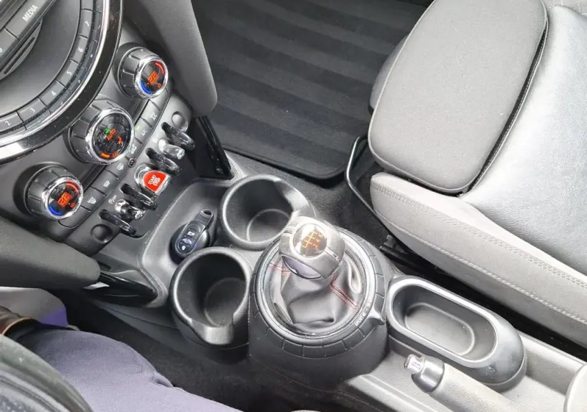 Vue intérieure centrée sur la console centrale et levier de vitesse manuel de la MINI S John Cooper Works 2015, sièges gris.