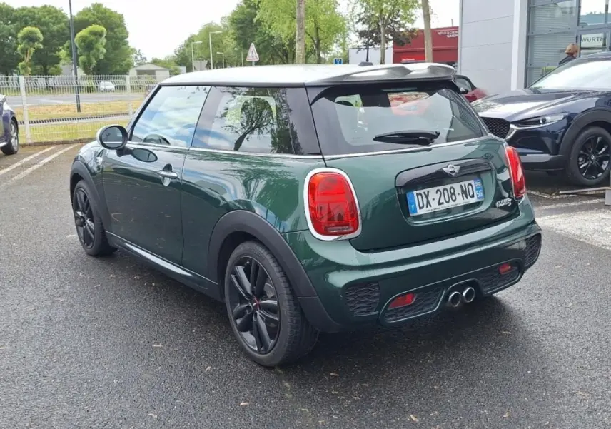 Vue 3/4 arrière droite d'une MINI S John Cooper Works 2015 vert foncé avec toit blanc et jantes noires.