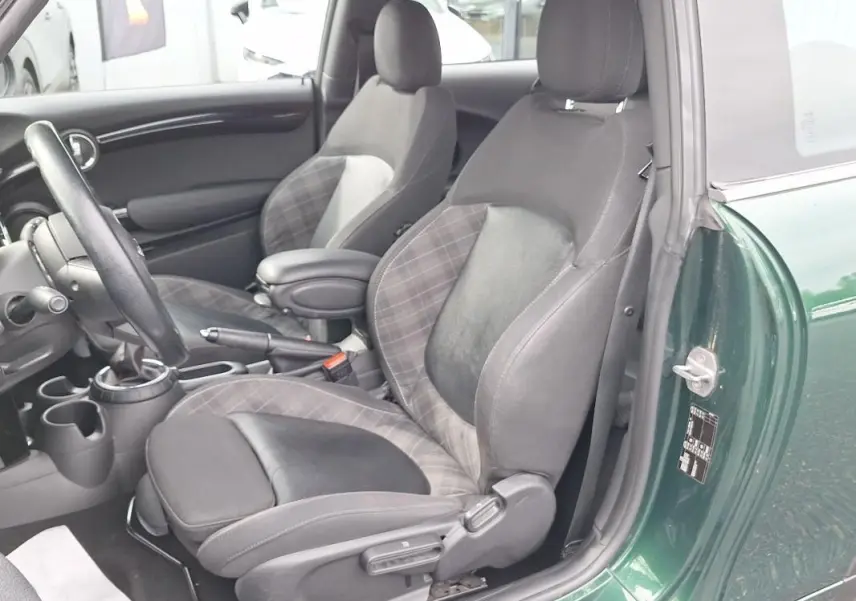 Vue intérieure côté conducteur d’une MINI S John Work 2015 avec sièges en tissu et cuir noir, portière verte ouverte.