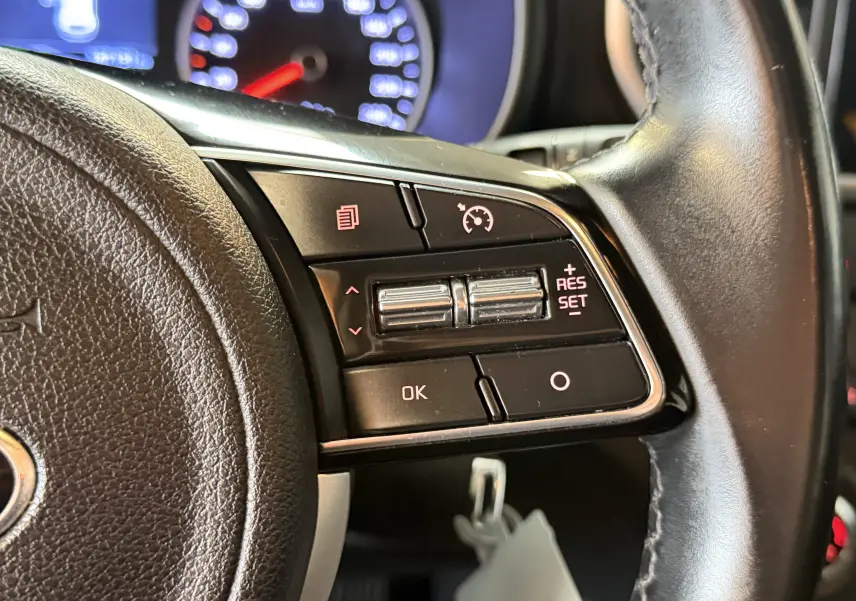 Gros plan sur les commandes au volant côté droit du Kia Sportage gris 2019, avec régulateur de vitesse et boutons fonctionnels.