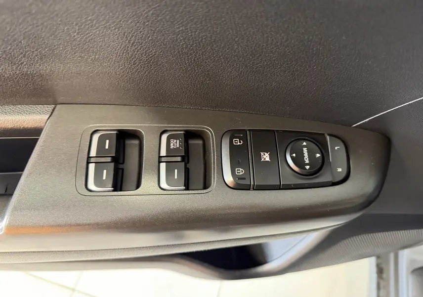Commande des vitres et rétroviseurs côté conducteur d’un KIA SPORTAGE gris 2019, vue rapprochée intérieure.