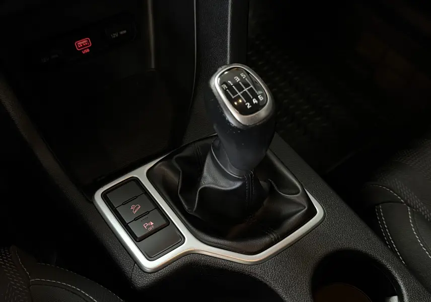 Gros plan sur le levier de vitesse manuel noir du KIA Sportage gris 2019 avec boutons de contrôle à proximité.