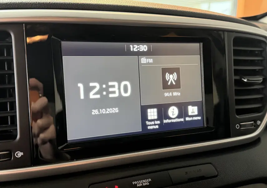 Écran tactile central du tableau de bord du Kia Sportage gris 2019, affichant l'heure et la radio FM.
