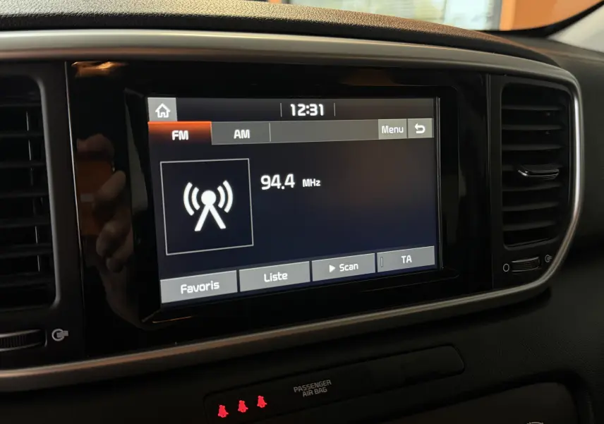 Écran tactile central de la KIA Sportage gris 2019 affichant la radio FM à 94,4 MHz en vue rapprochée intérieure.
