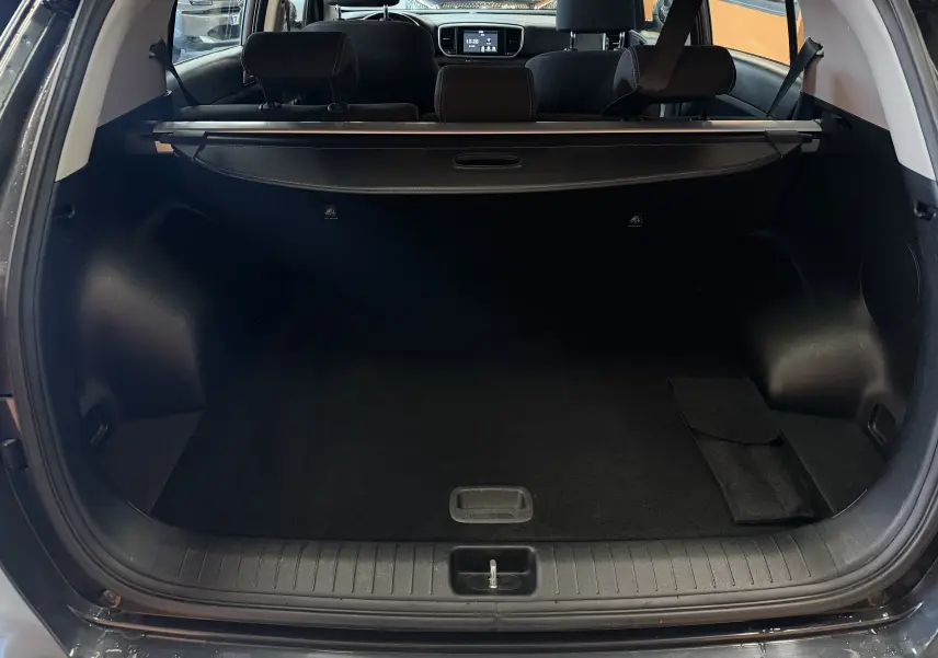 Vue arrière ouverte du coffre noir d’un KIA SPORTAGE gris 2019, avec cache-bagages et sièges arrière visibles.