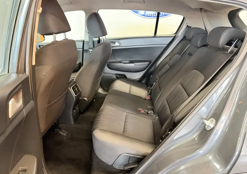 Vue intérieure côté gauche montrant la banquette arrière noire et les sièges avant d’un KIA Sportage gris 2019.