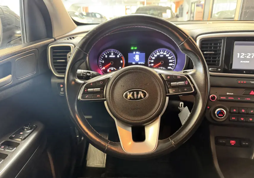 Vue intérieure centrée sur le volant noir du Kia Sportage 2019, avec tableau de bord et commandes visibles.