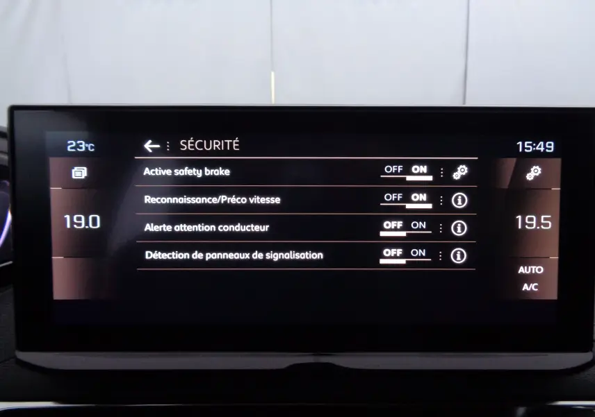 Tableau de bord numérique du Peugeot 5008 gris platinium, affichant les réglages de sécurité et la climatisation.