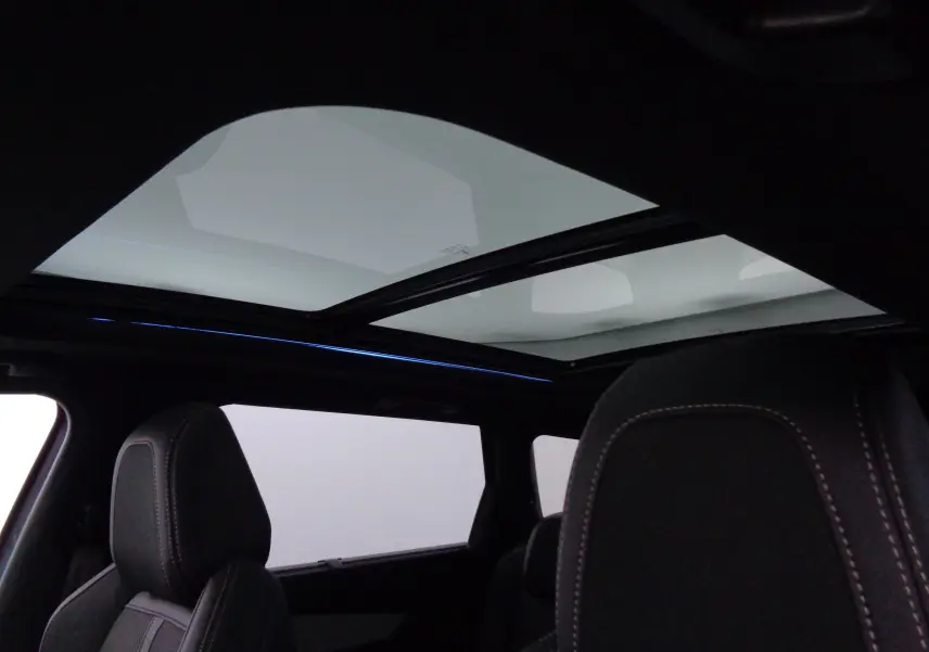 Vue intérieure du Peugeot 5008 GT 2023 montrant le toit panoramique et les sièges avant en cuir noir avec surpiqûres contrastées.