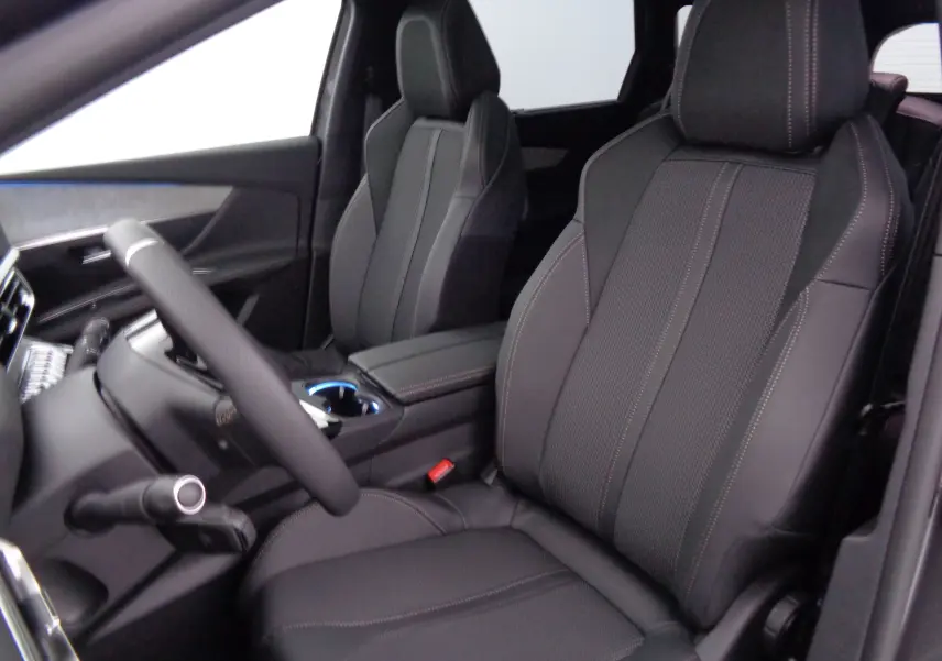 Vue intérieure du Peugeot 5008 2023, sièges avant en cuir noir avec surpiqûres contrastées, volant visible côté gauche.