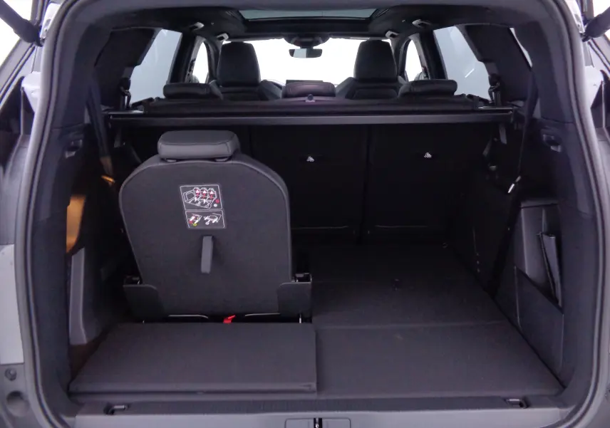 Vue arrière ouverte du coffre du Peugeot 5008 gris platinium, montrant les sièges arrière rabattables et l'espace de chargement.