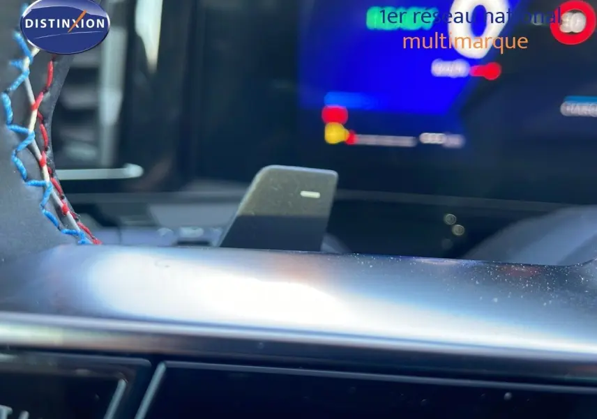 Gros plan sur le levier de vitesses automatique et le volant surpiqué bleu et rouge du Renault Espace hybride 2025.