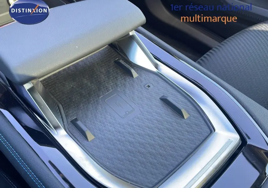 Gros plan sur la console centrale noire du Renault Espace 2025 avec tapis de recharge sans fil et accoudoir gris clair.
