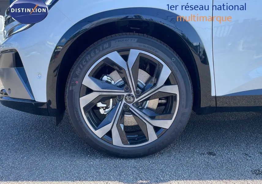 Gros plan sur la roue avant gauche du Renault Espace blanc nacré 2025, mettant en valeur la jante alliage bicolore moderne.