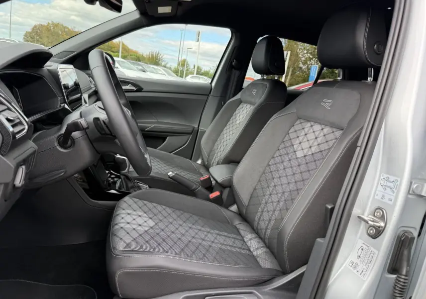 Vue intérieure côté conducteur du Volkswagen T-Cross gris cendre 2025 avec sièges R-Line en tissu et alcantara.