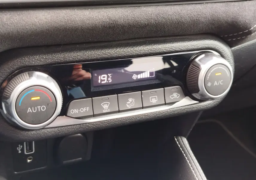 Gros plan sur la commande de climatisation digitale affichant 19,5°C dans l'habitacle noir de la Nissan Micra N-Sport.