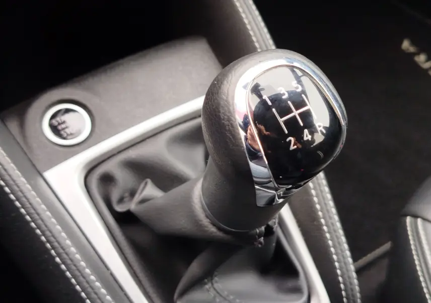 Le levier de vitesses manuel noir de la Nissan Micra 2022 avec surpiqûres blanches et bouton start/stop visible.