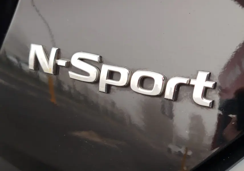 Gros plan sur l'insigne N-Sport argenté sur la carrosserie noire brillante d'une Nissan Micra 2022.