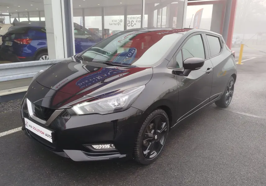 Nissan Micra 2022 noir obscur vue 3/4 avant droit, avec jantes noires et phares LED allumés.