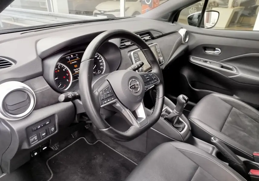 Intérieur noir de la Nissan Micra 2022, vue côté conducteur sur le volant, tableau de bord et levier de vitesses manuel.