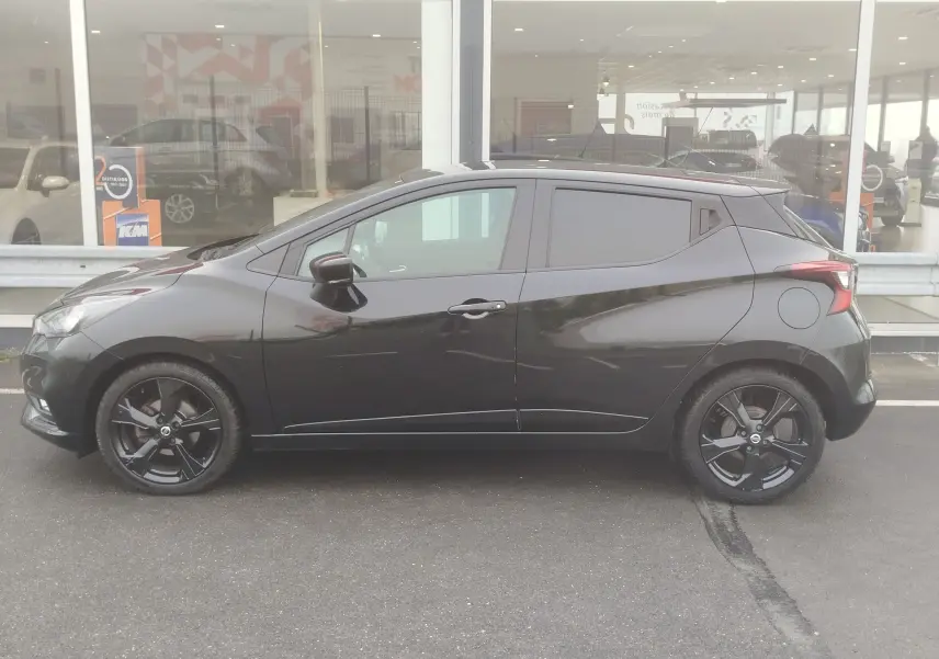 Profil côté gauche d'une Nissan Micra 2022 noire avec jantes noires et lignes dynamiques visibles en extérieur.