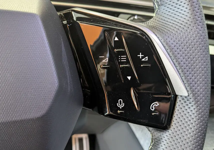 Gros plan sur les commandes tactiles noires à droite du volant perforé d’un Peugeot 3008 Bleu Ingara 2026.