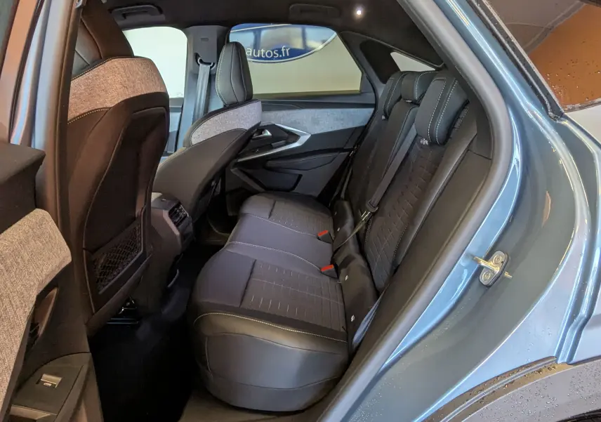 Vue intérieure côté arrière droit du Peugeot 3008 1.2 Hybrid 145ch GT bleu Ingaro, montrant les sièges arrière en tissu et cuir.