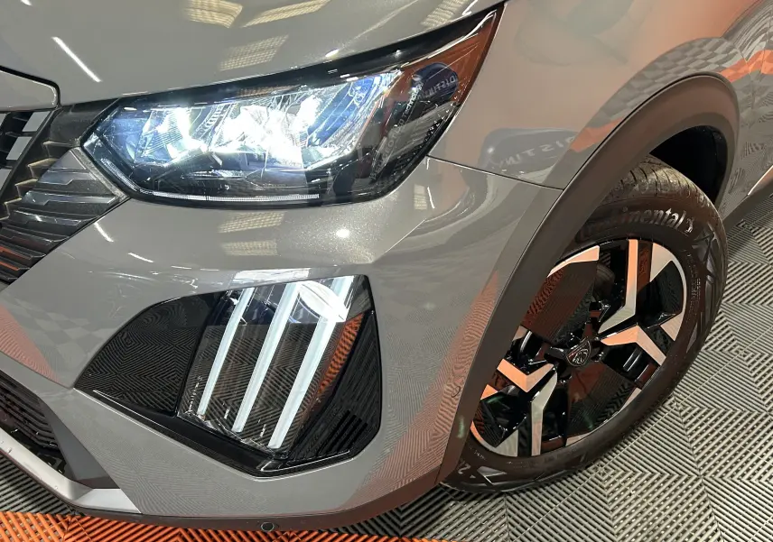 Gros plan sur l'avant droit gris Selenium du Peugeot 2008 II Ph.2, mettant en valeur les phares LED et la jante bicolore.