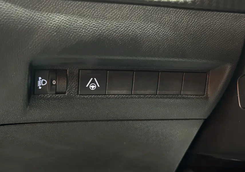 Détail intérieur des commandes d'assistance à la conduite sur tableau de bord noir du Peugeot 2008 gris Selenium.