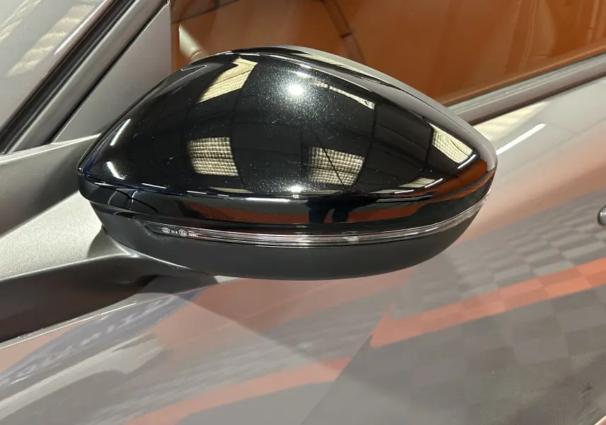 Rétroviseur noir brillant côté gauche du Peugeot 2008 gris Selenium, vue rapprochée sur la carrosserie métallique.