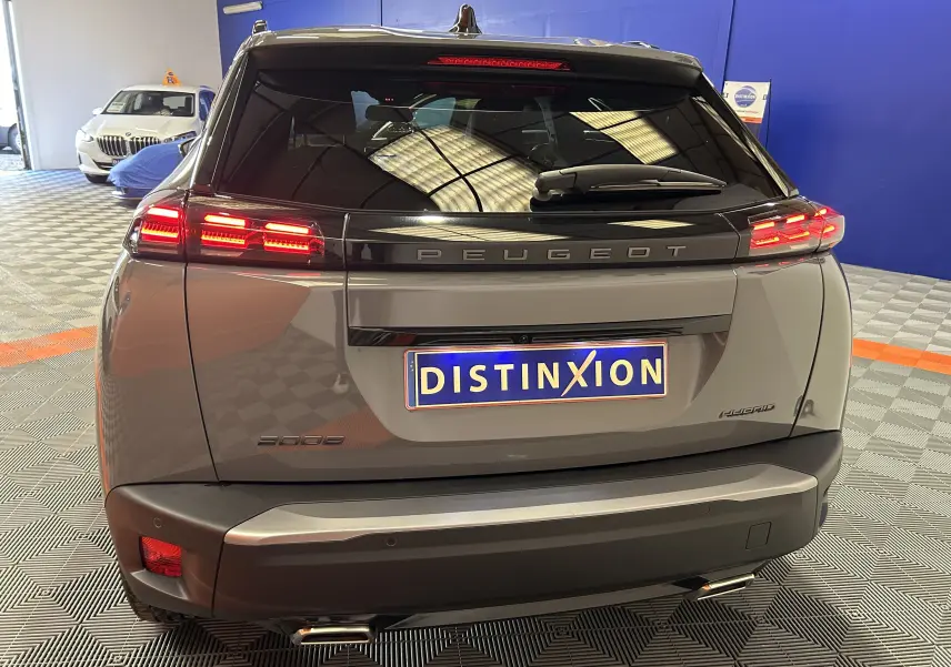 Vue arrière du Peugeot 2008 gris Selenium avec feux LED allumés et plaque d'immatriculation Distinxion en intérieur showroom.