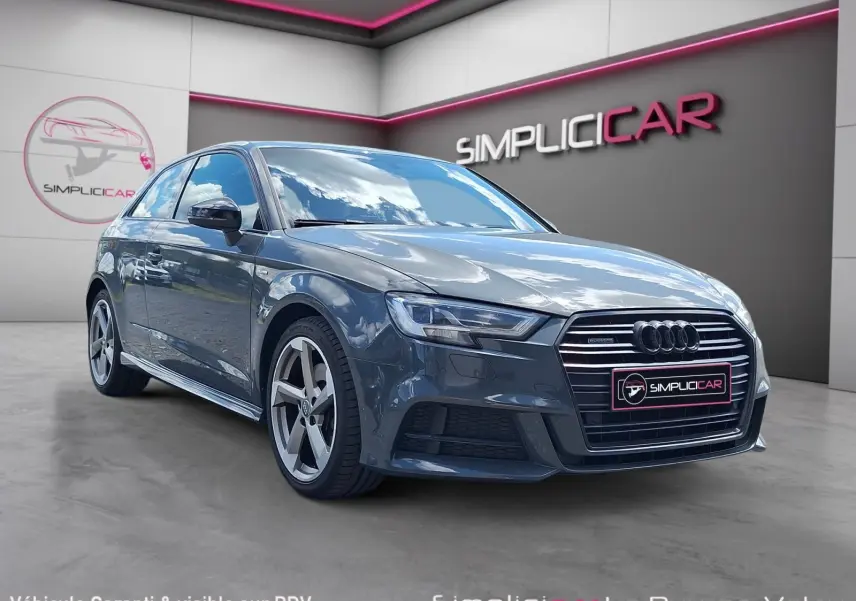 Audi A3 gris en 3/4 avant droit, avec calandre S Line et jantes alliage 18 pouces visibles en showroom.