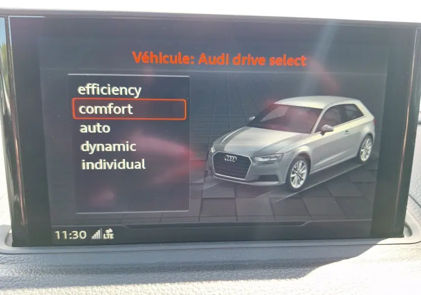 Écran intérieur montrant une Audi A3 gris clair en 3/4 avant droit avec menu de sélection mode de conduite.
