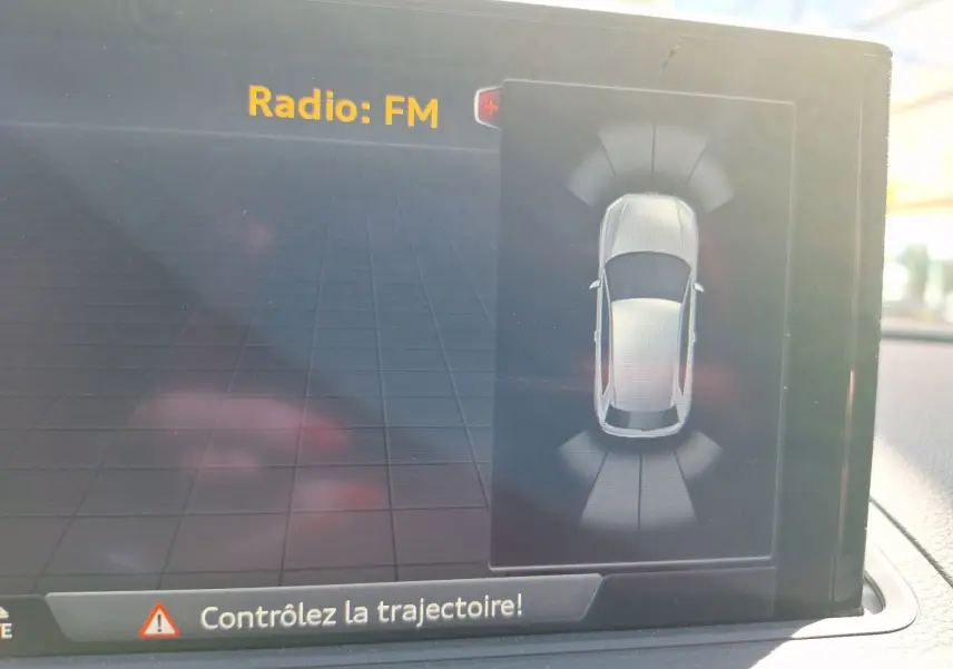 Écran intérieur affichant l'aide au stationnement avec vue aérienne du véhicule gris Audi A3 2017 en mode Park Assist.