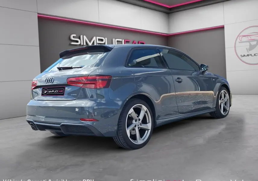 Audi A3 2.0 TFSI S Line gris vue 3/4 arrière droit, jantes alliage 18 pouces et toit spoiler noir.