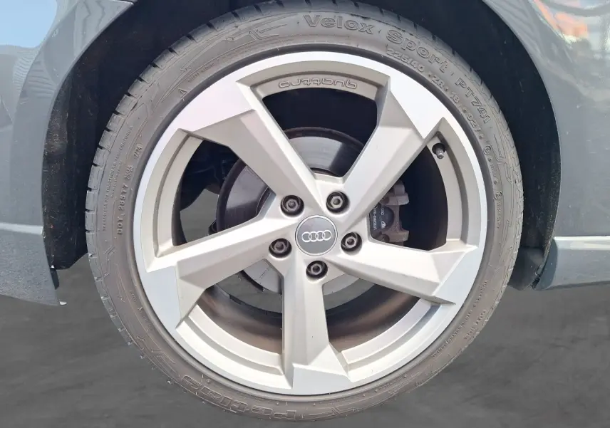 Gros plan sur la jante alliage 18 pouces grise avec logo Audi, sur la roue avant droite de l'Audi A3 gris.