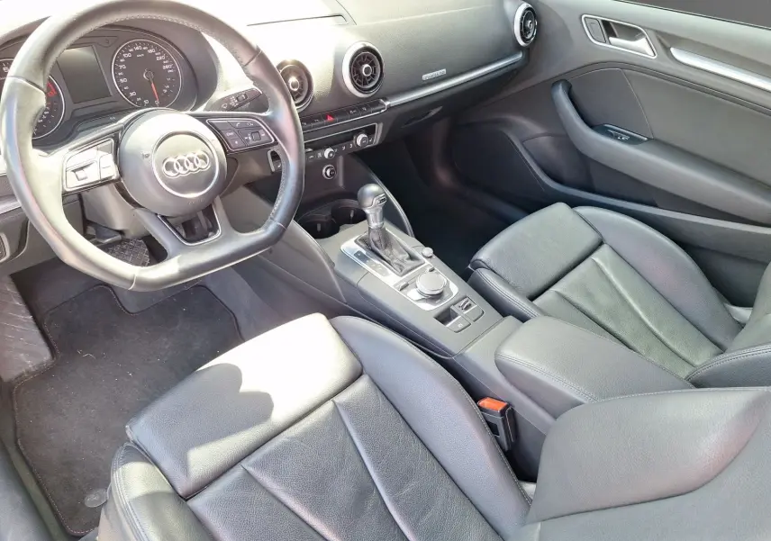 Vue intérieure côté conducteur de l'Audi A3 2017, sellerie cuir noire et console centrale avec levier de boîte automatique.