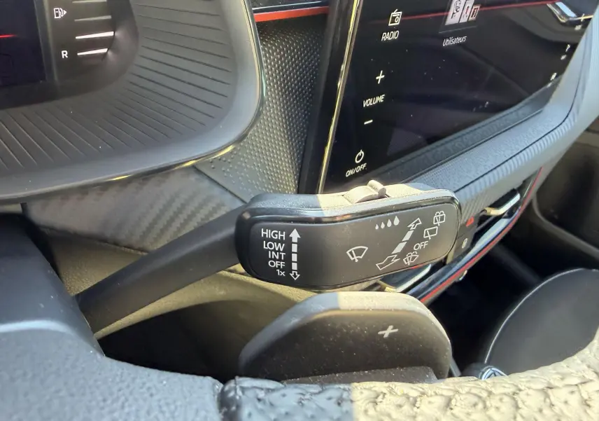Gros plan sur la commande d’essuie-glace et le volant sport en cuir du Skoda Kamiq 2025, intérieur noir avec écran tactile.