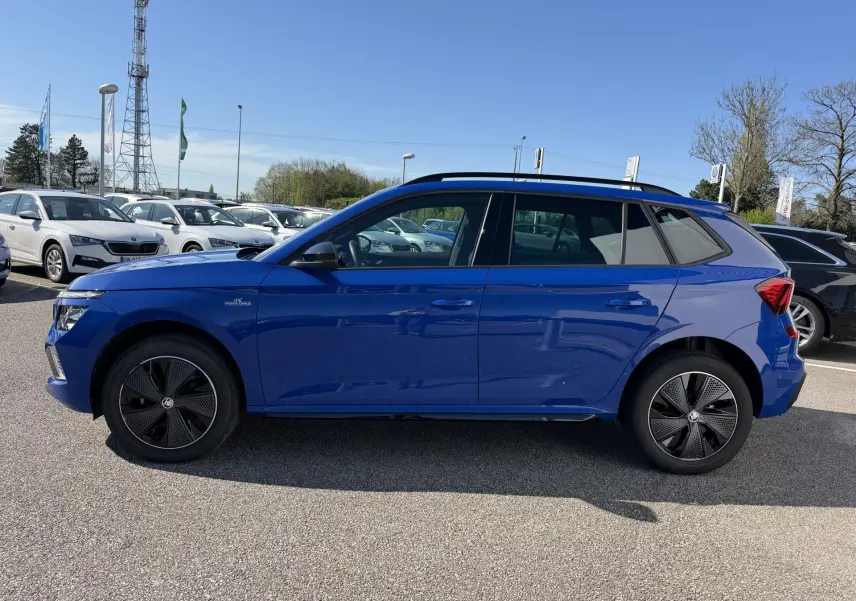 Vue de profil côté gauche d'un Skoda Kamiq bleu avec jantes alliage noires et toit ouvrant panoramique.