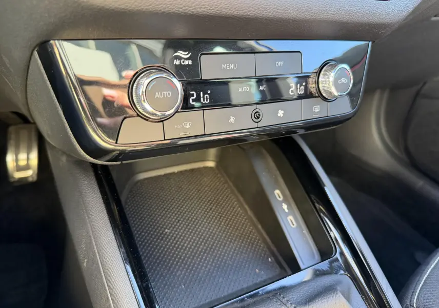 Gros plan sur la console centrale du Skoda Kamiq 2025, avec climatisation automatique bi-zone et surface de recharge sans fil.