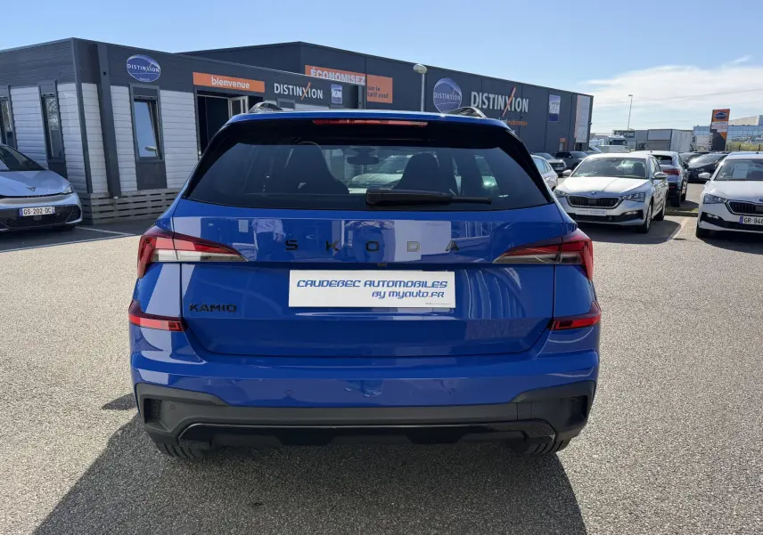 Vue arrière d'un Skoda Kamiq bleu 2025 avec feux arrière LED et logo SKODA visible sur un parking extérieur.