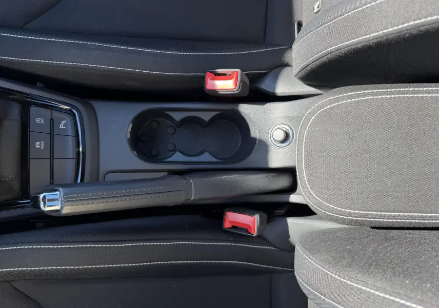 Vue plongeante sur la console centrale noire du Skoda Kamiq 2025, avec frein à main manuel et porte-gobelets.
