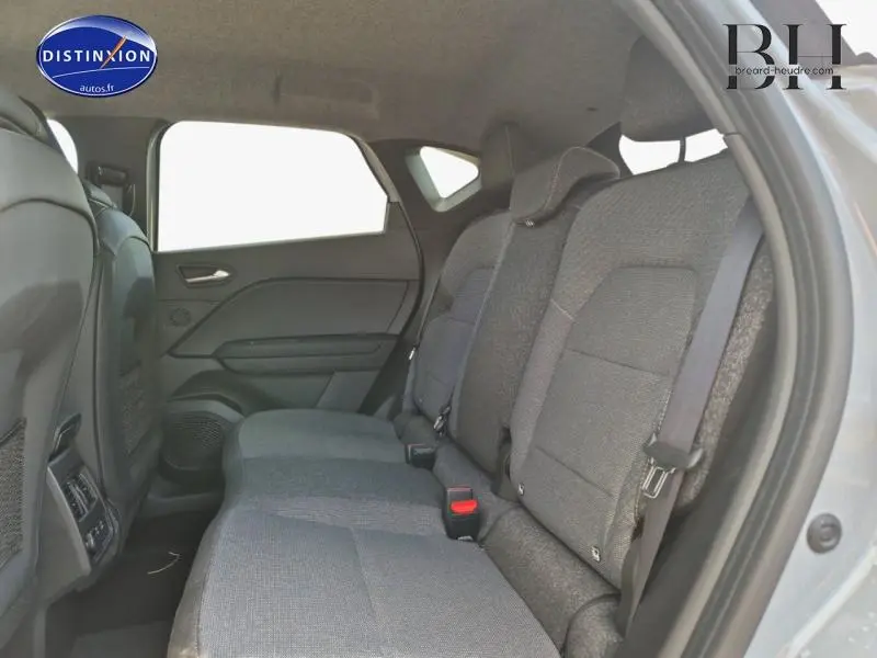 Vue latérale droite de l'intérieur arrière du Renault Captur 2025, sièges tissu gris foncé et ceintures visibles.